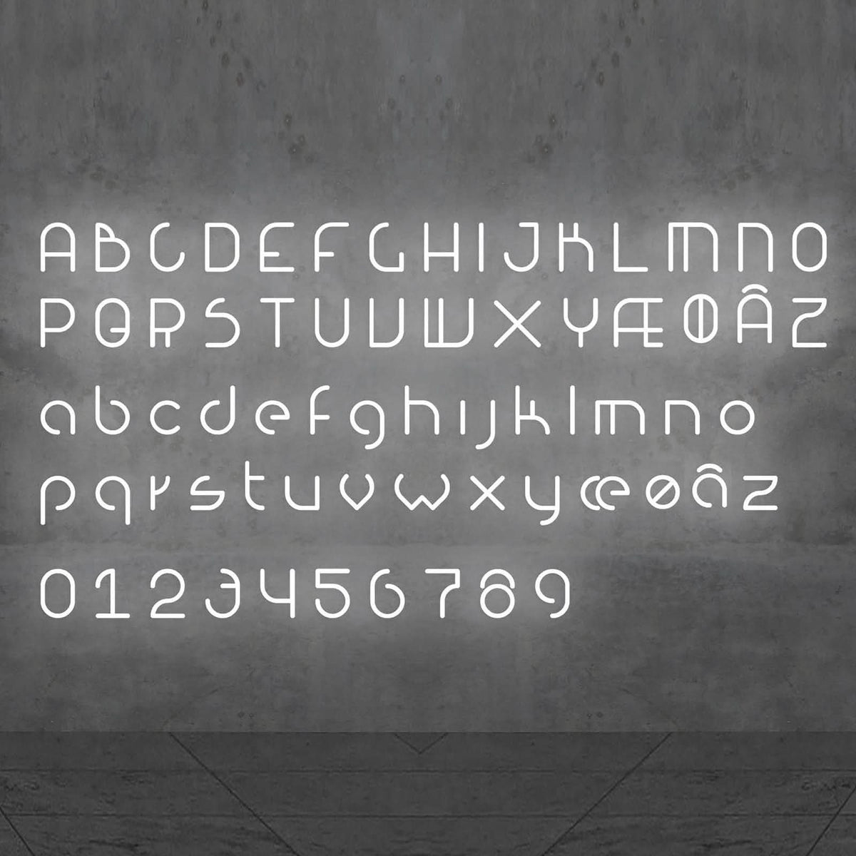 Alphabet complet et chiffres en lettres LED blanches disposés sur un mur gris.