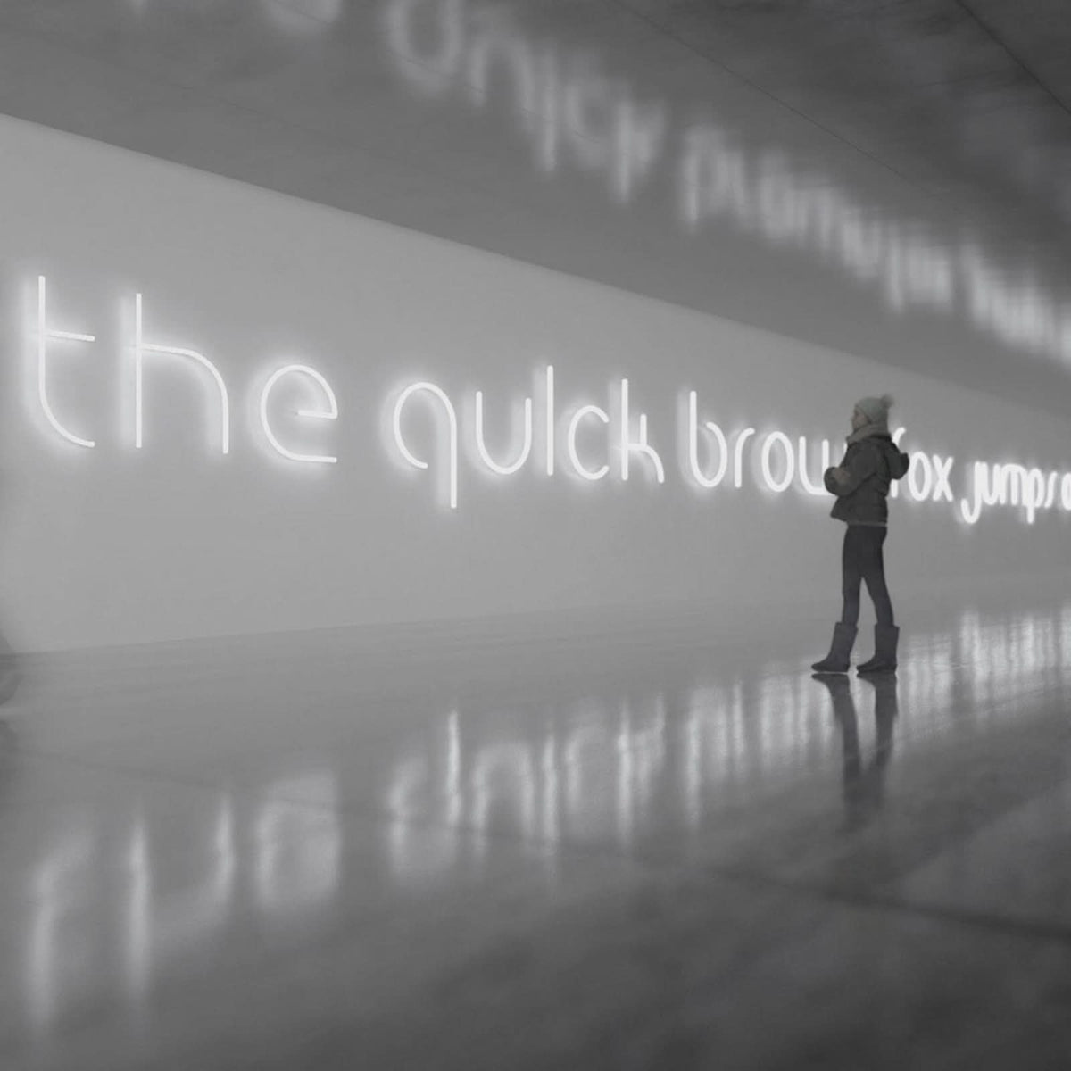 Une femme contemple une longue phrase lumineuse blanche reflétée sur le sol