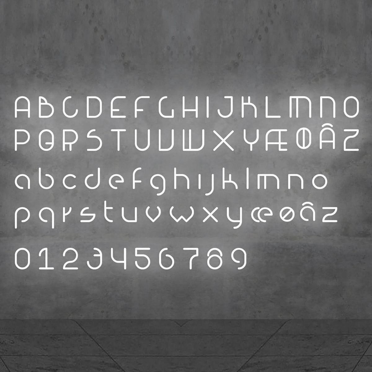 Alphabet complet en lettres et chiffres lumineux blancs présenté sur un mur gris.