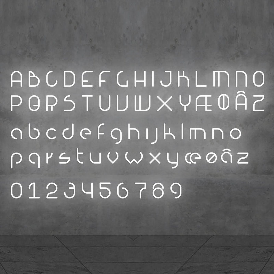 Alphabet complet en lettres et chiffres lumineux blancs présenté sur un mur gris.