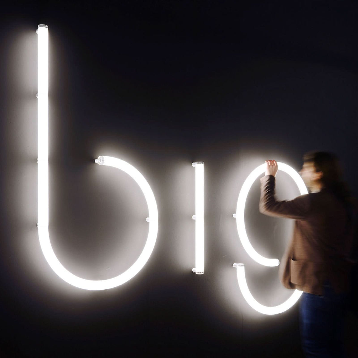 Personne touchant de grandes lettres lumineuses bio sur fond sombre