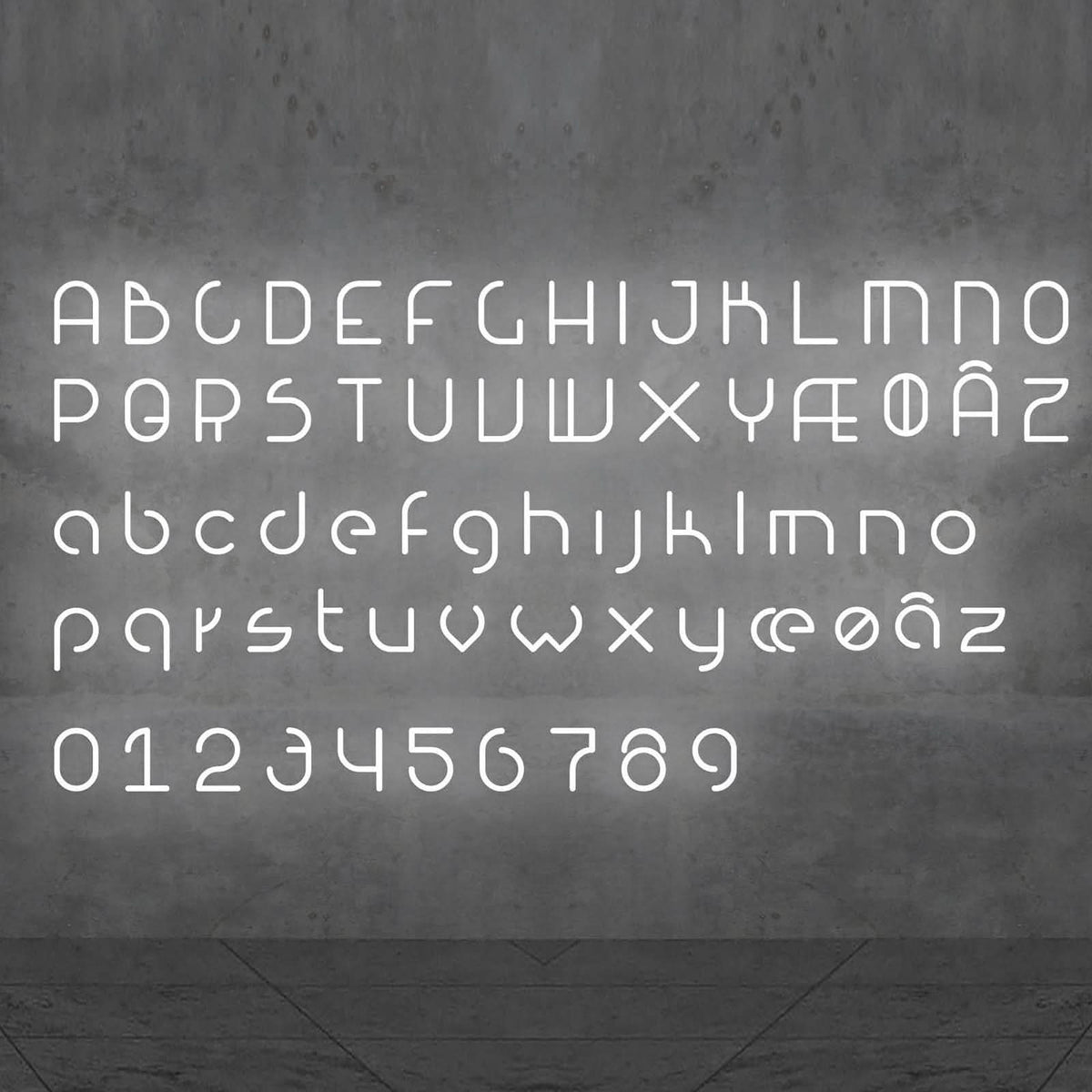 Alphabet complet de lettres et chiffres lumineux blancs disposés sur une paroi grise.