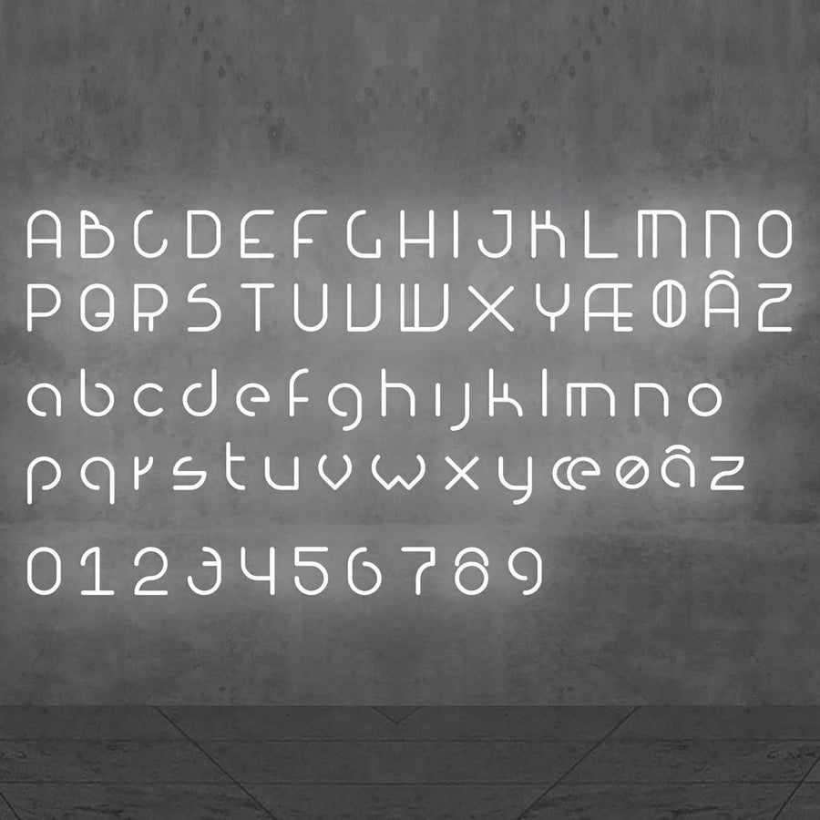Alphabet complet lumineux, majuscules, minuscules et chiffres, présenté sur un mur béton.