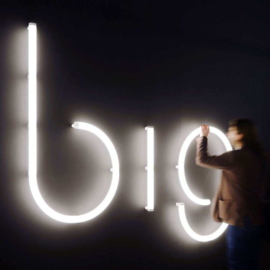 Personne installant les grandes lettres lumineuses bio sur un mur noir