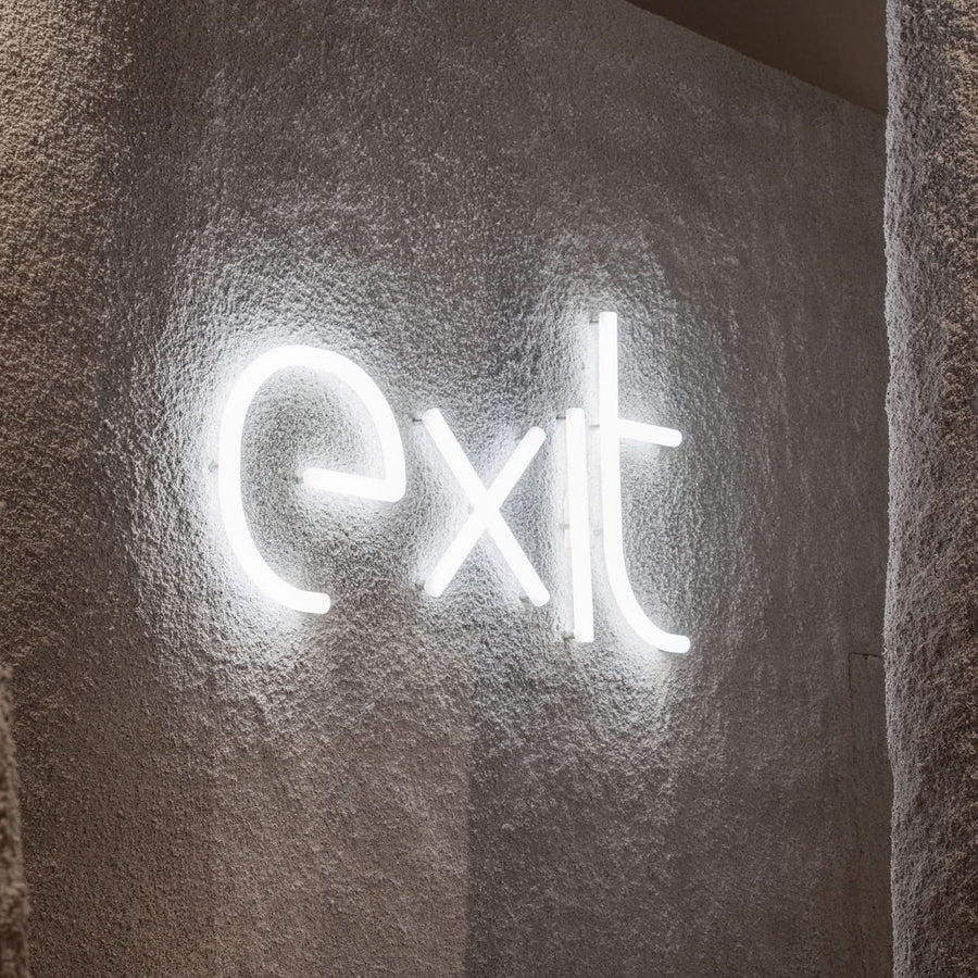 Détail du mot exit en lettres lumineuses sur un mur texturé