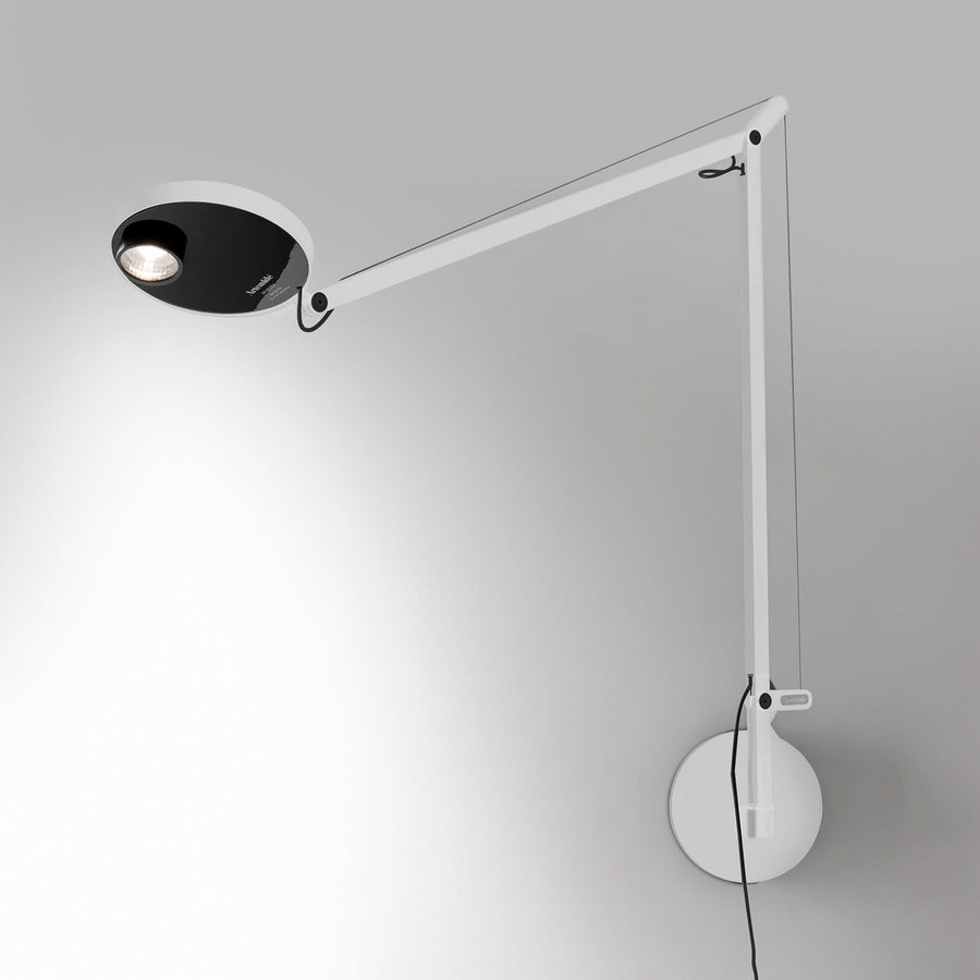 Applique murale blanche articulée avec tête noire ronde allumée sur mur clair