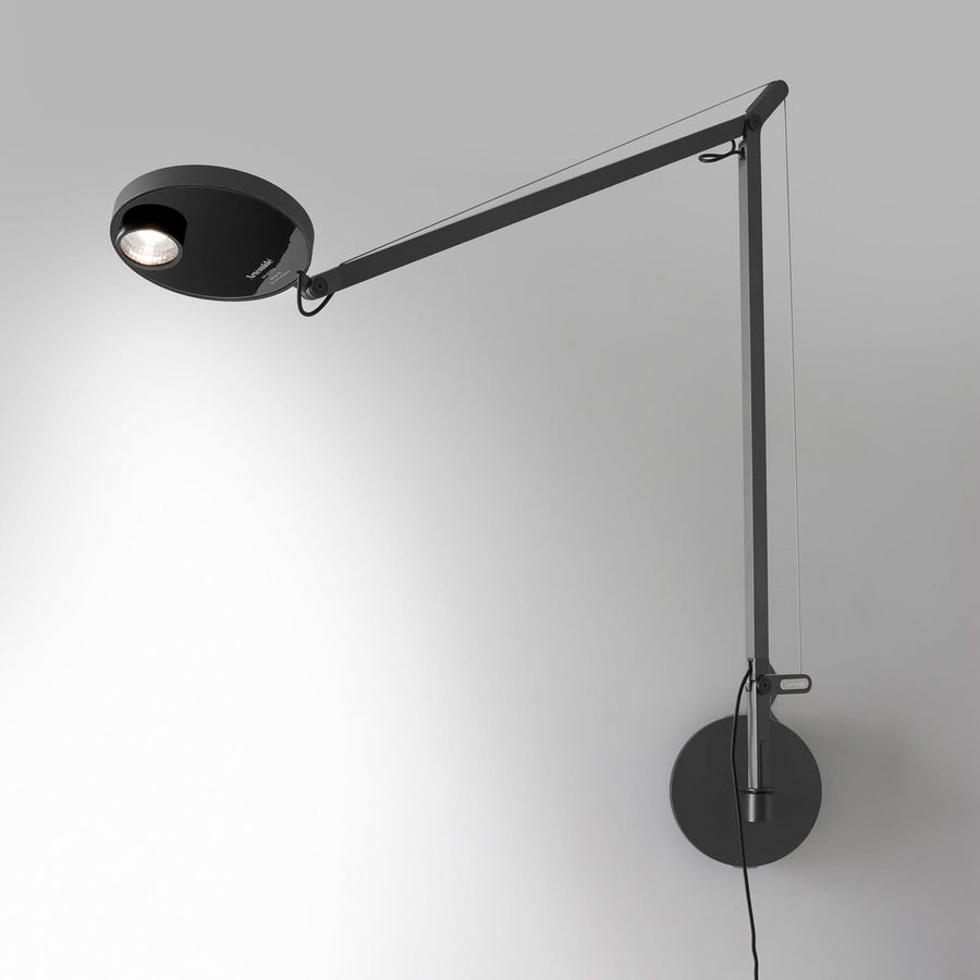 Applique murale anthracite à bras articulé et tête ronde, fixée sur un mur clair
