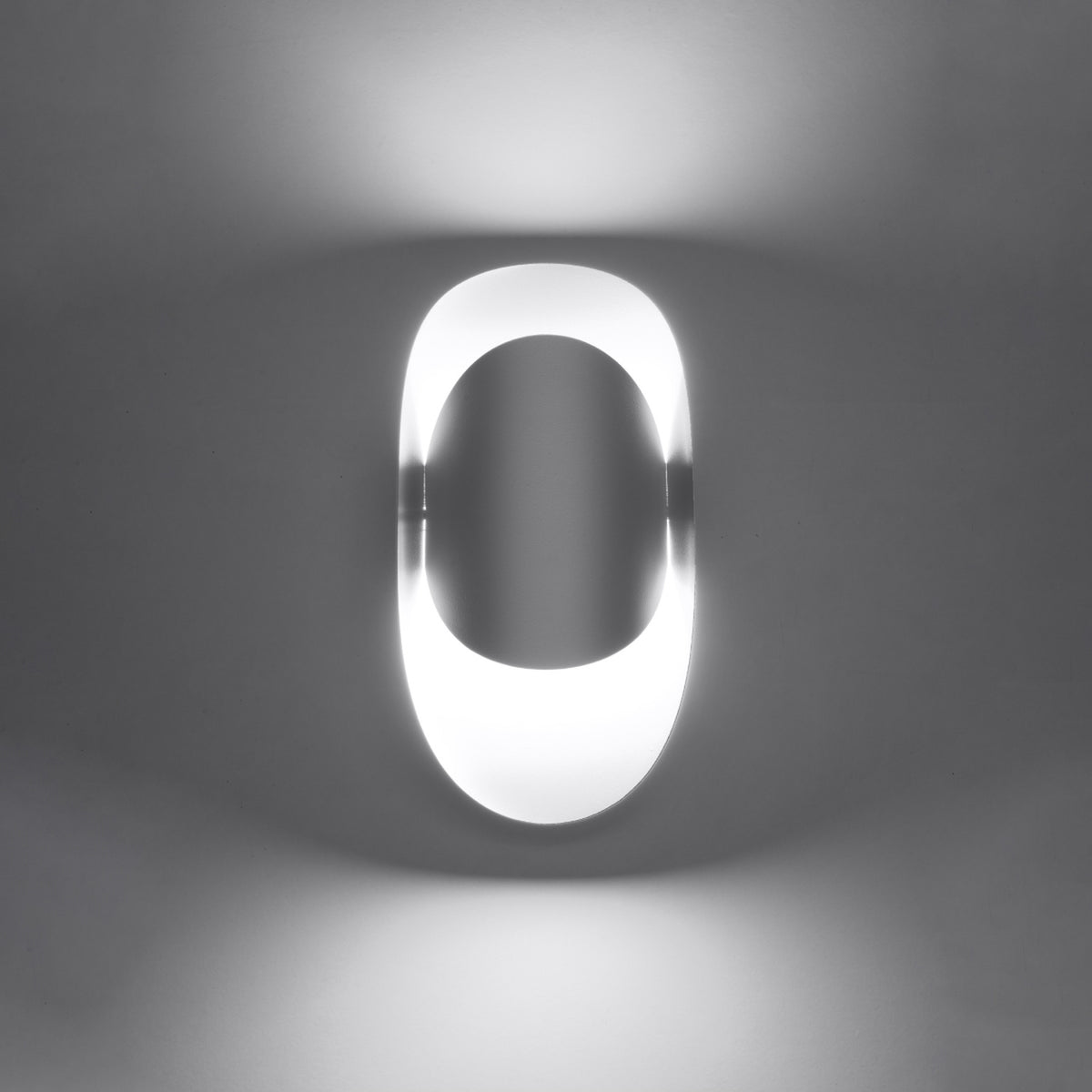 Luminaire allumé dans la pénombre, halo lumineux diffus autour du boîtier ovale