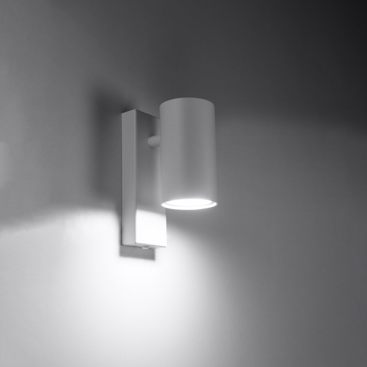 Applique allumée dans la pénombre, halo lumineux projeté sur le mur.