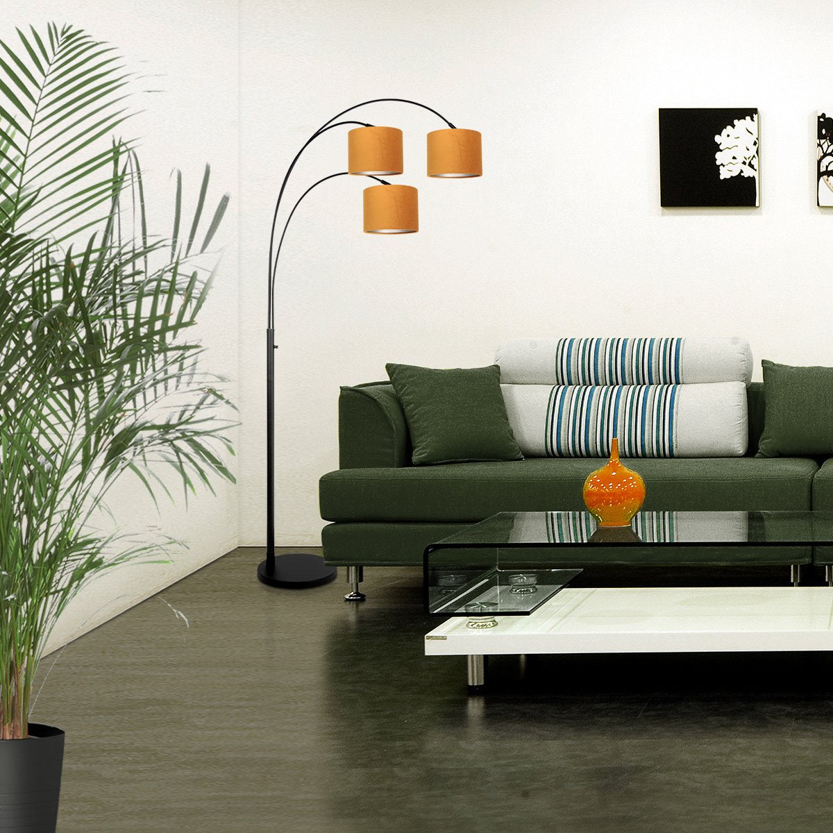 Mise en ambiance dans un salon avec canapé vert et lampadaire allumé.