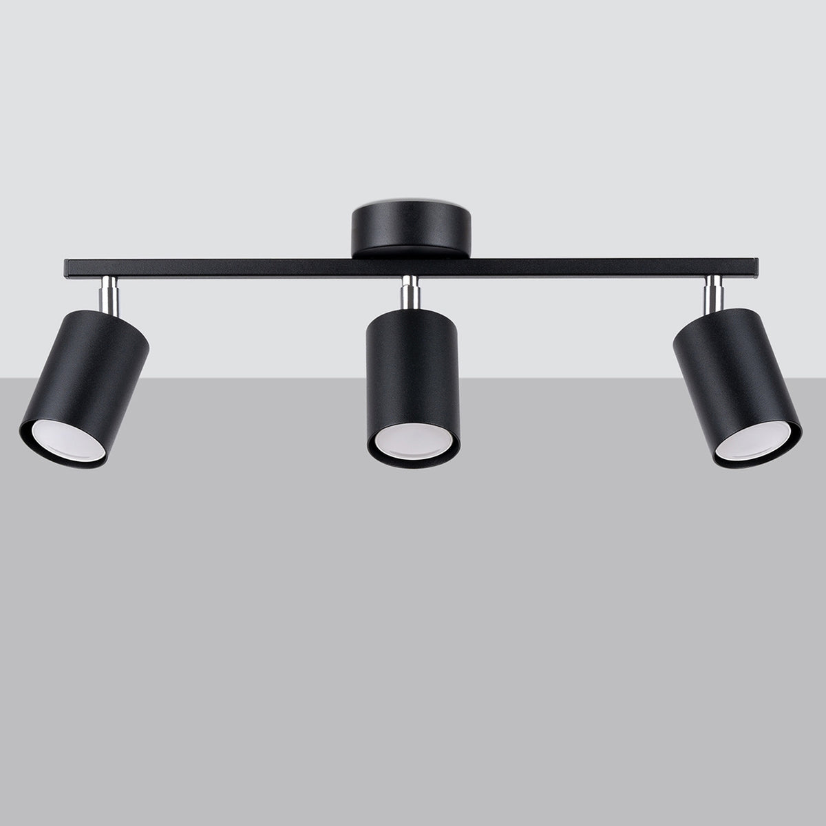 Plafonnier trois spots noirs suspendu sur fond gris clair, orientable.