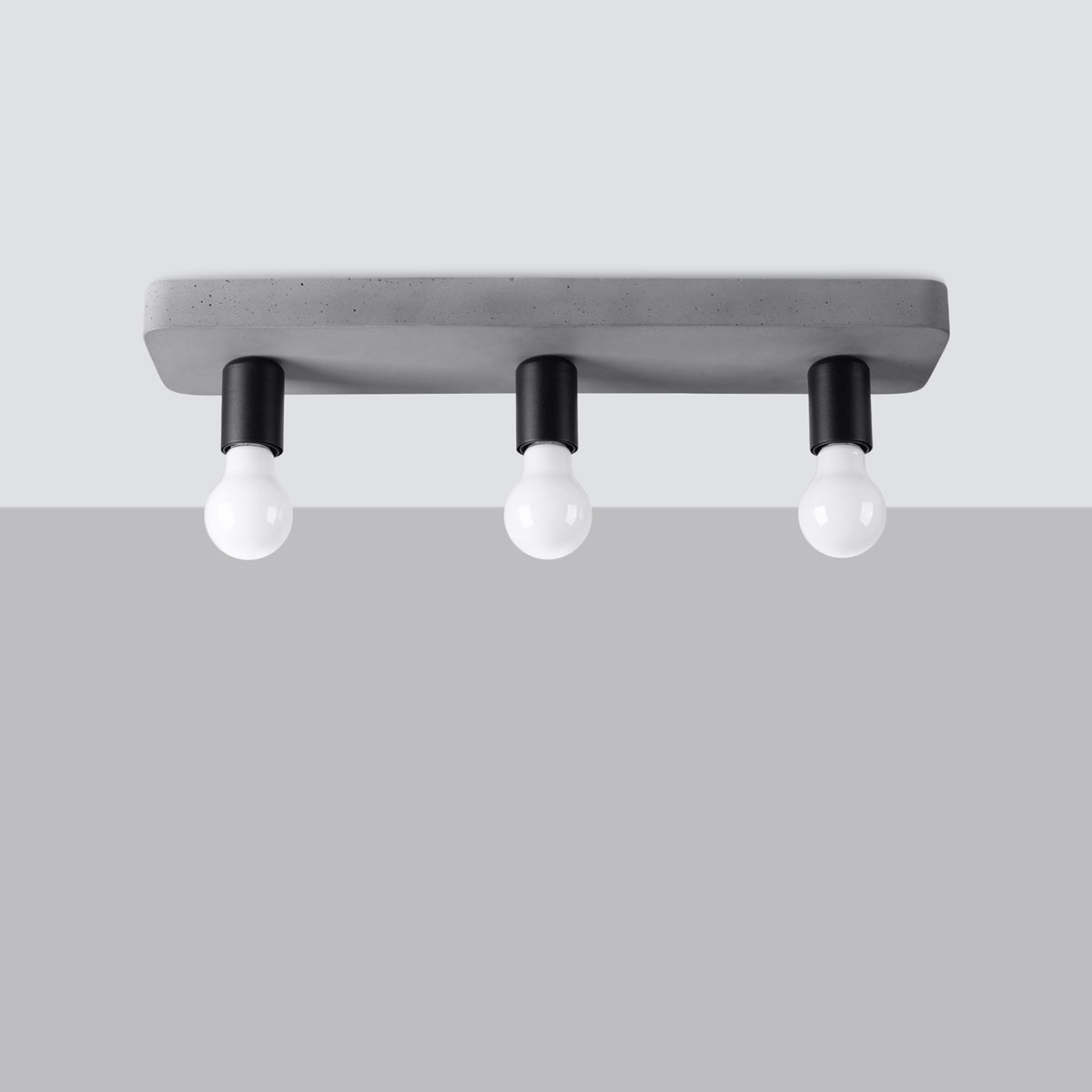 Vue de face sur fond gris clair du luminaire avec trois ampoules blanches allumées.