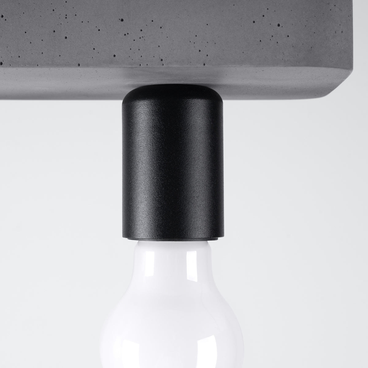 Détail rapproché d'une douille noire texturée et d'une ampoule blanche vissée.