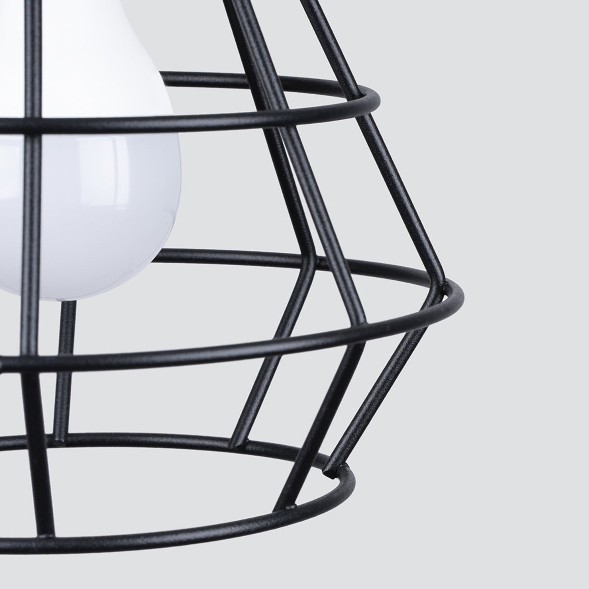 Détail rapproché de la cage métallique noire et de l'ampoule blanche à l'intérieur.