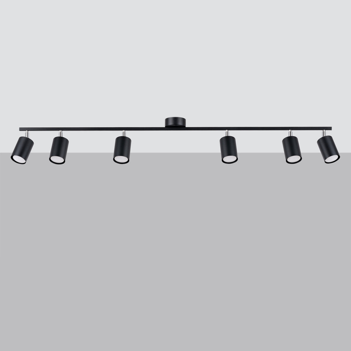 Luminaire noir vu de face devant un mur gris clair, spots légèrement inclinés
