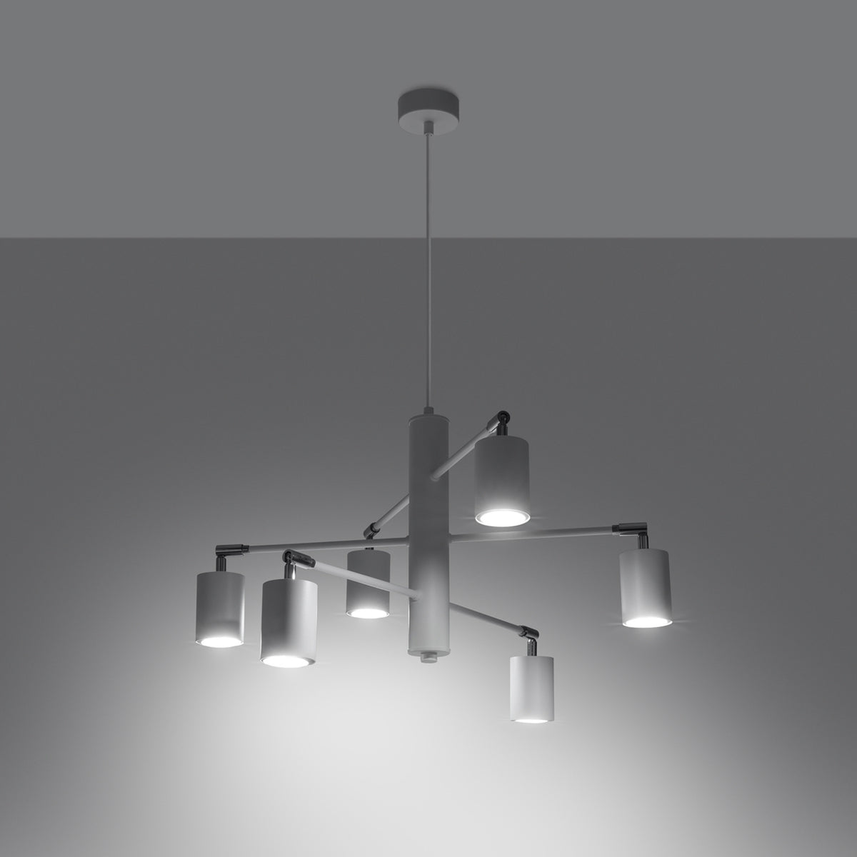 Luminaire suspendu en fonctionnement dans une pièce sombre, six cylindres diffusent une lumière blanche uniforme.