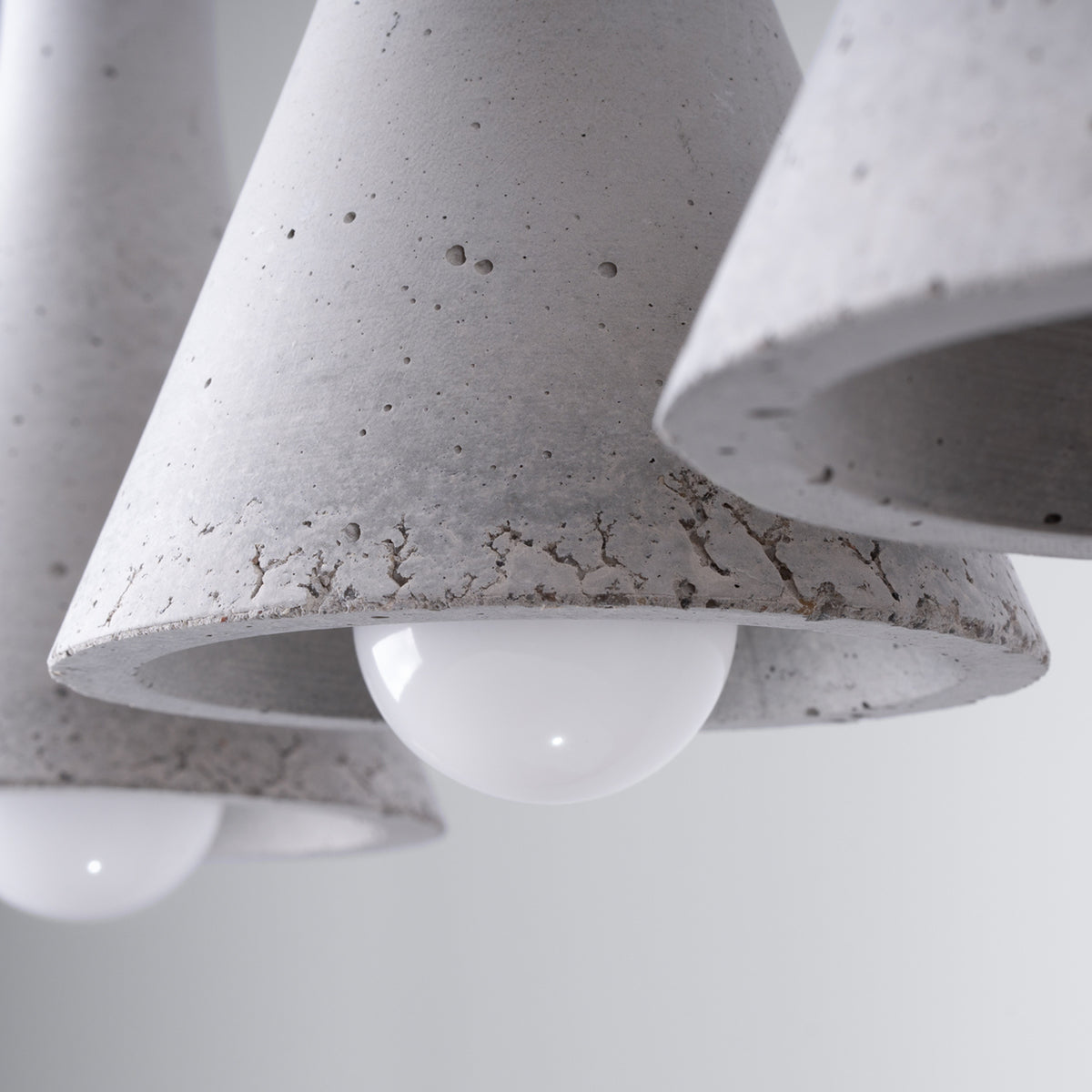 Gros plan sur la texture brute du béton et l'ampoule blanche à l'intérieur.