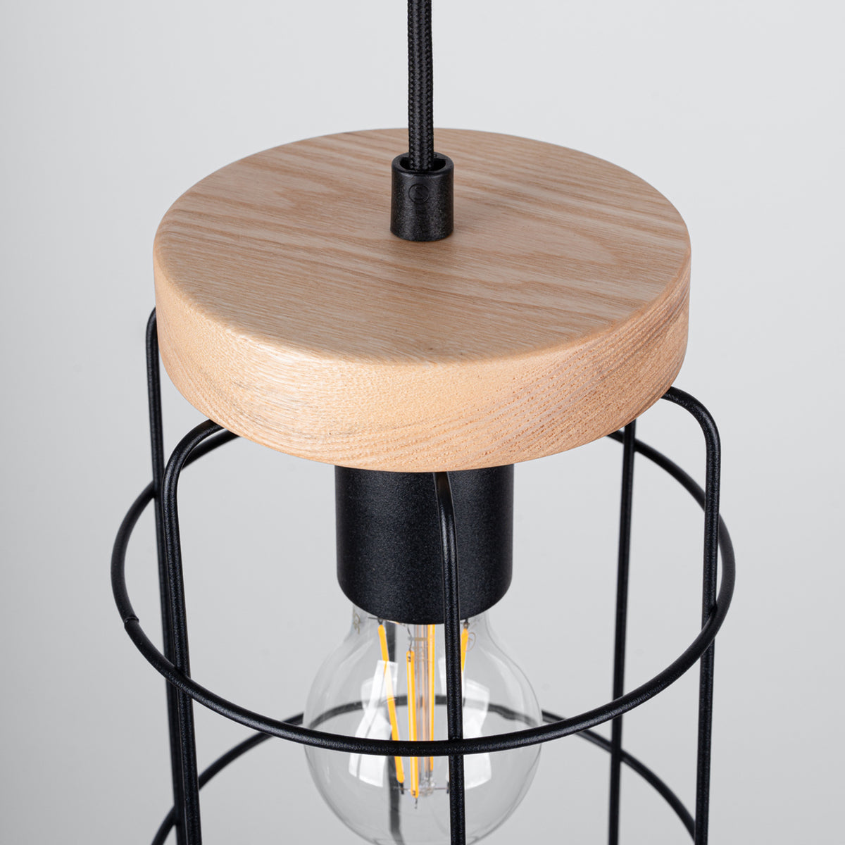 Détail rapproché d'une suspension montrant la finition bois, la douille et l'ampoule LED.