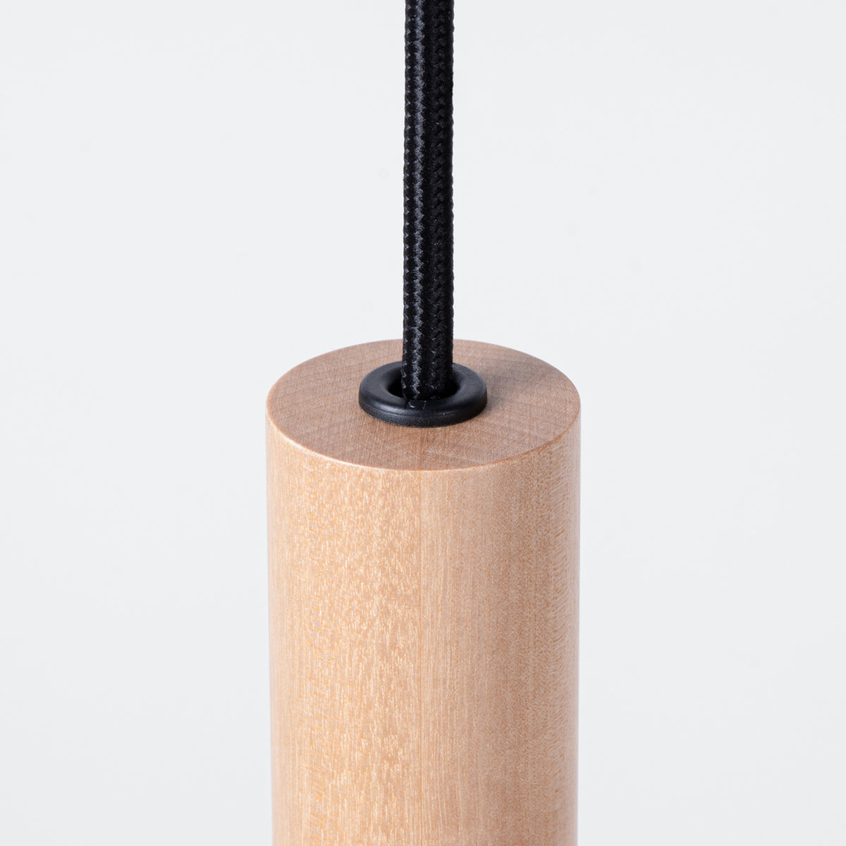 Détail du haut d'un cylindre en bois, cordon noir et œillet de finition.