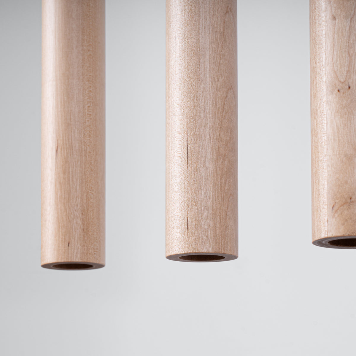 Détail rapproché de trois tubes en bois clair, veinage et embouts ouverts.
