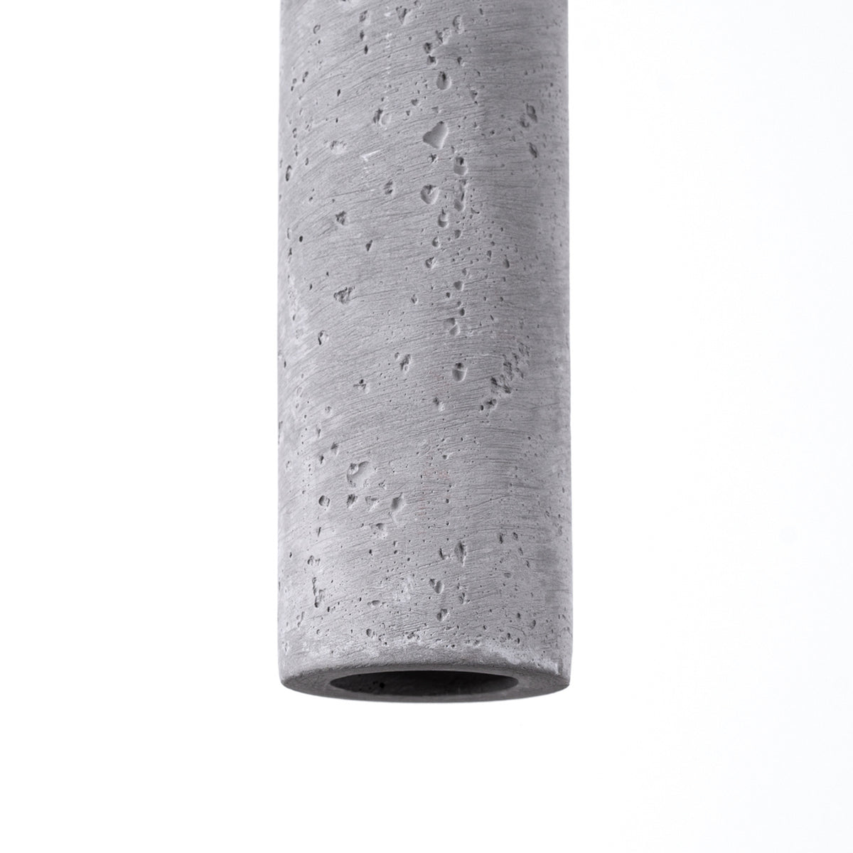 Détail de la finition béton brut, texture poreuse et ouverture circulaire en bas.