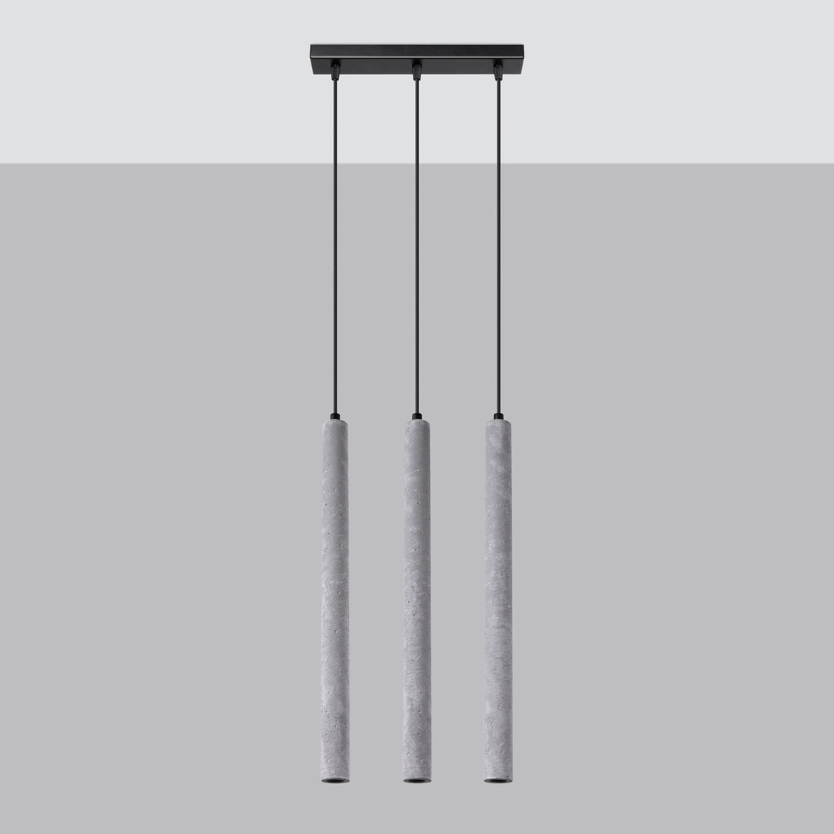 Vue de face du luminaire à trois suspensions cylindriques en béton sur fond gris.
