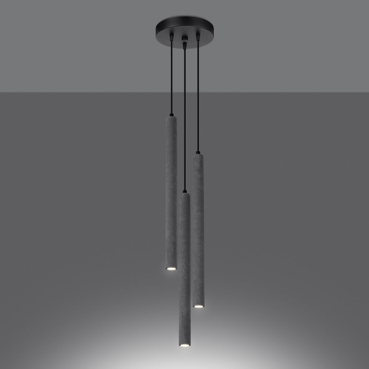 Ambiance sombre : les trois tubes en béton s'allument en bas, halo lumineux.