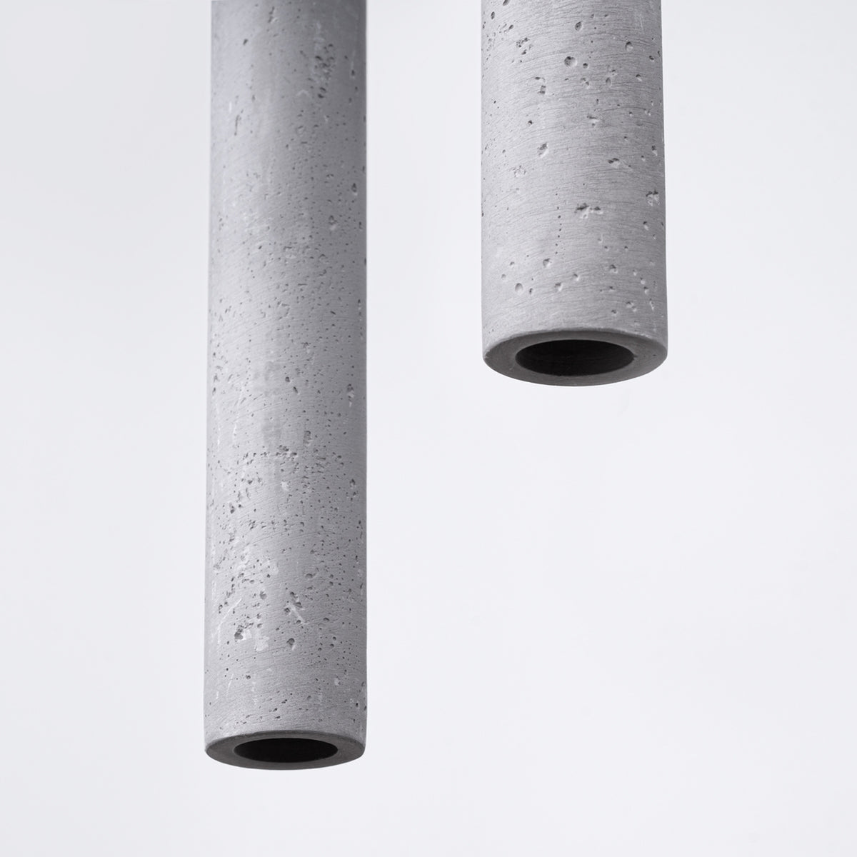 Gros plan sur deux tubes en béton brut montrant la texture poreuse et l'ouverture noire.