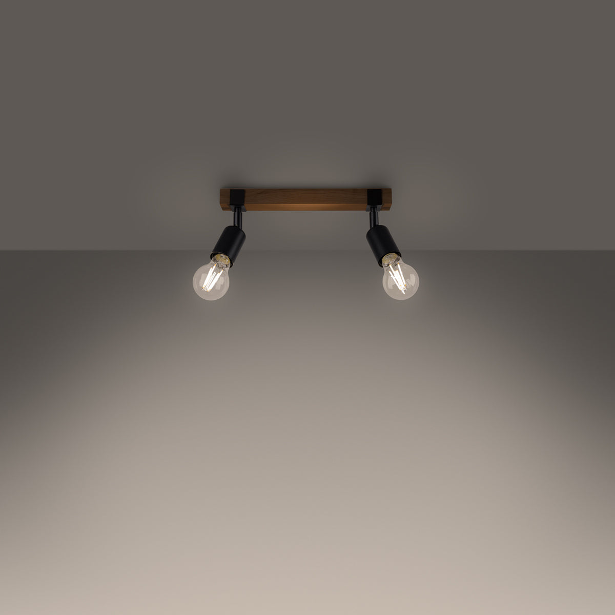 Luminaire allumé au plafond, deux ampoules diffusent une lumière chaude sur le mur.