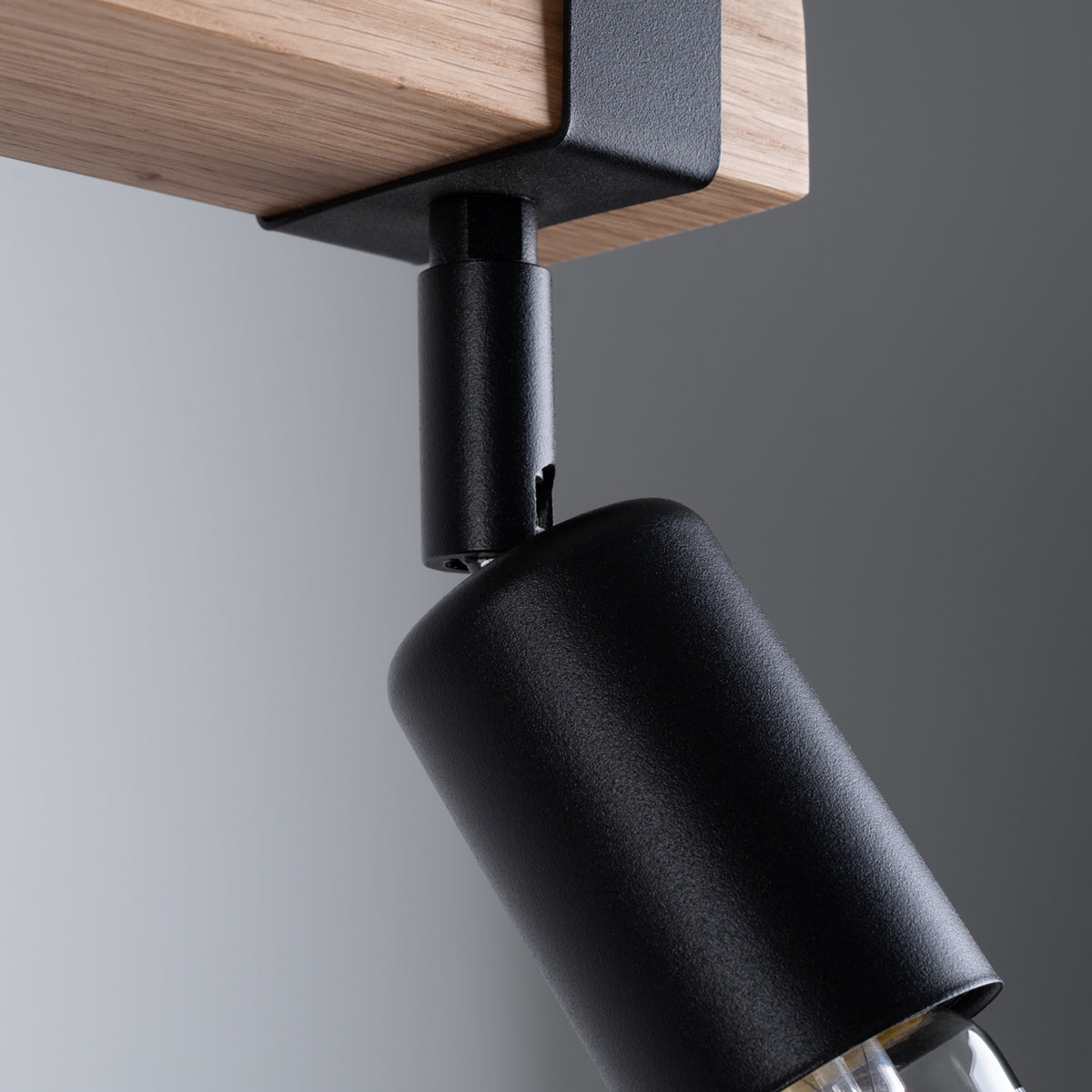 Gros plan sur un spot noir orientable et la fixation sur la barre en bois.