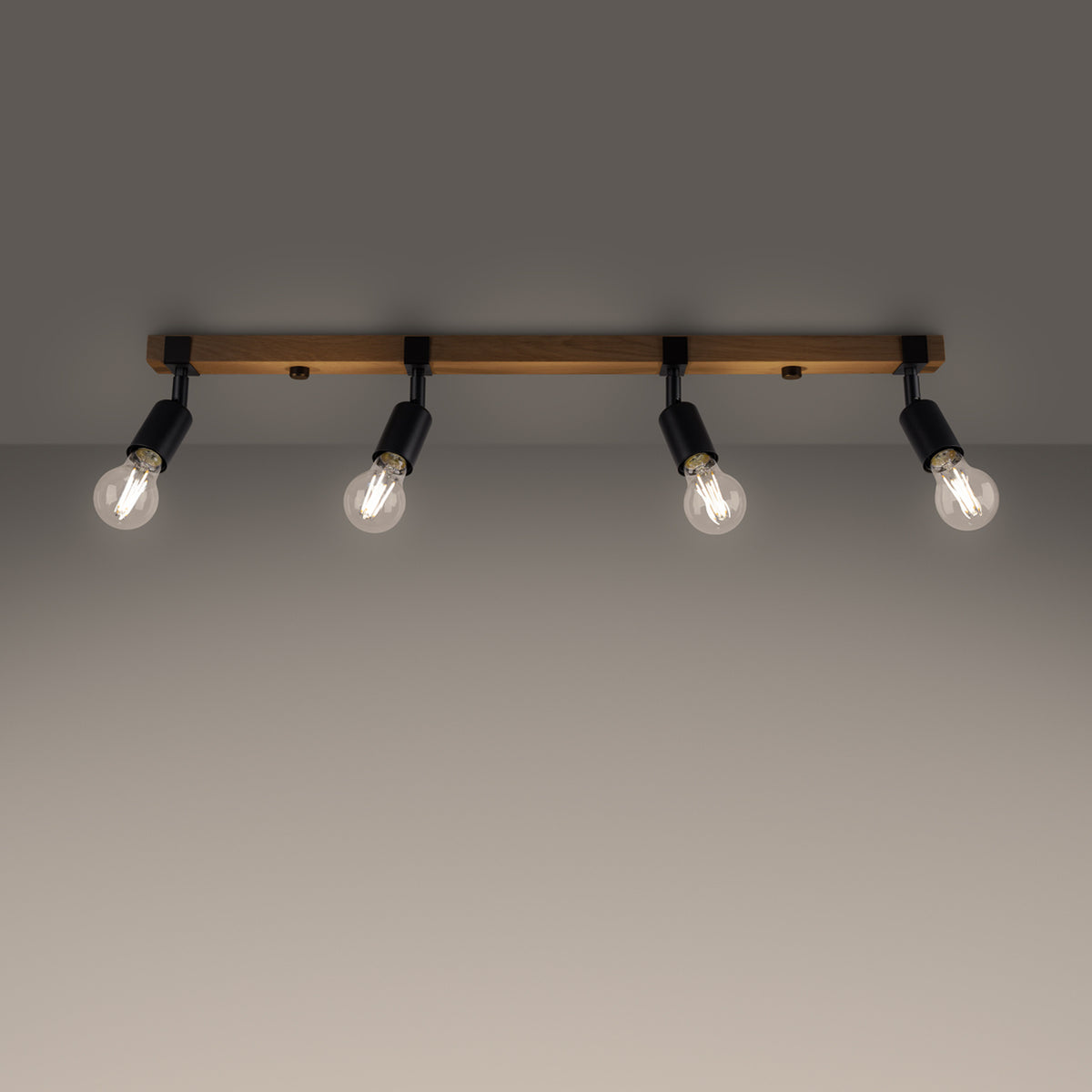 Plafonnier allumé dans une pièce sombre, les quatre ampoules diffusent une lumière chaude.