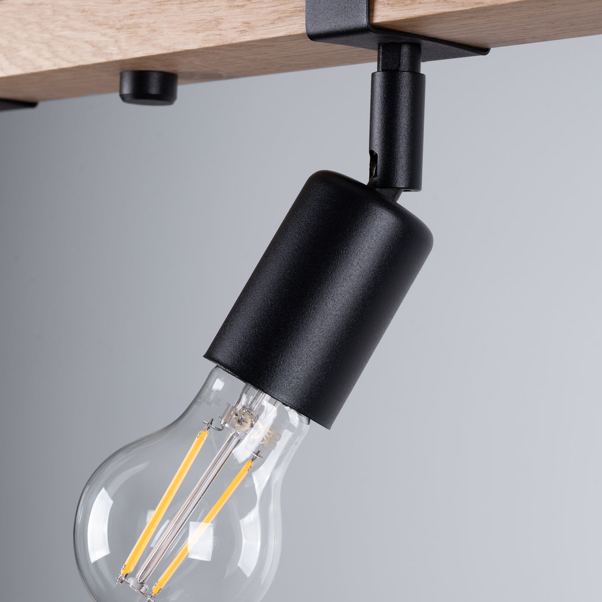 Gros plan sur la douille noire et une ampoule filament transparente.
