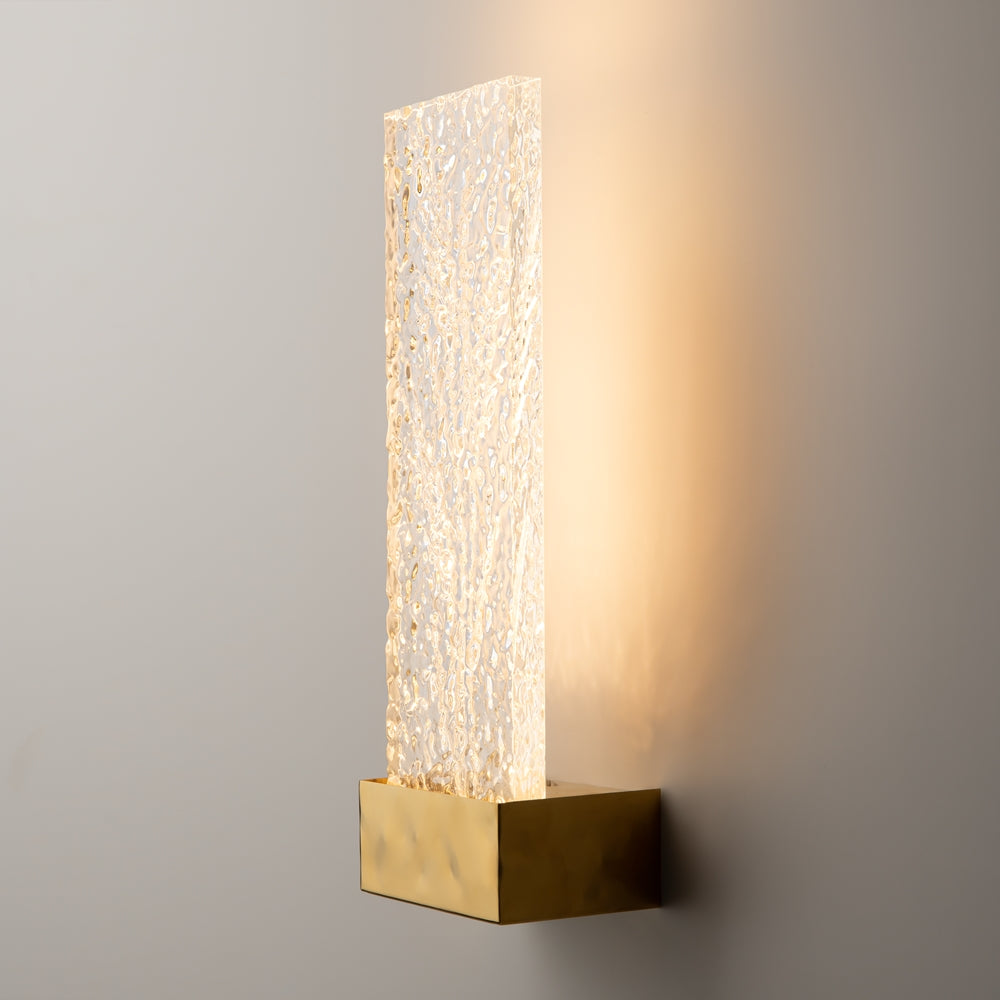 Vue de trois quarts de l'applique allumée projetant une lumière chaude sur le mur.
