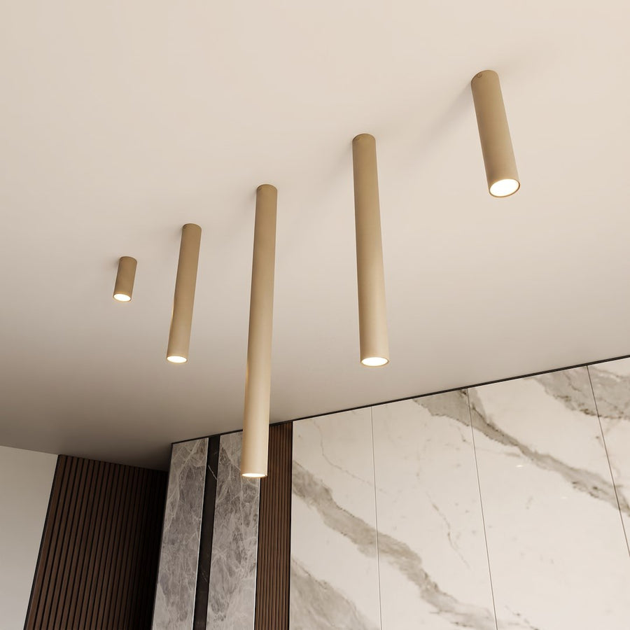 Gros plan sur plusieurs cylindres beige fixés au plafond, éclairant une pièce.