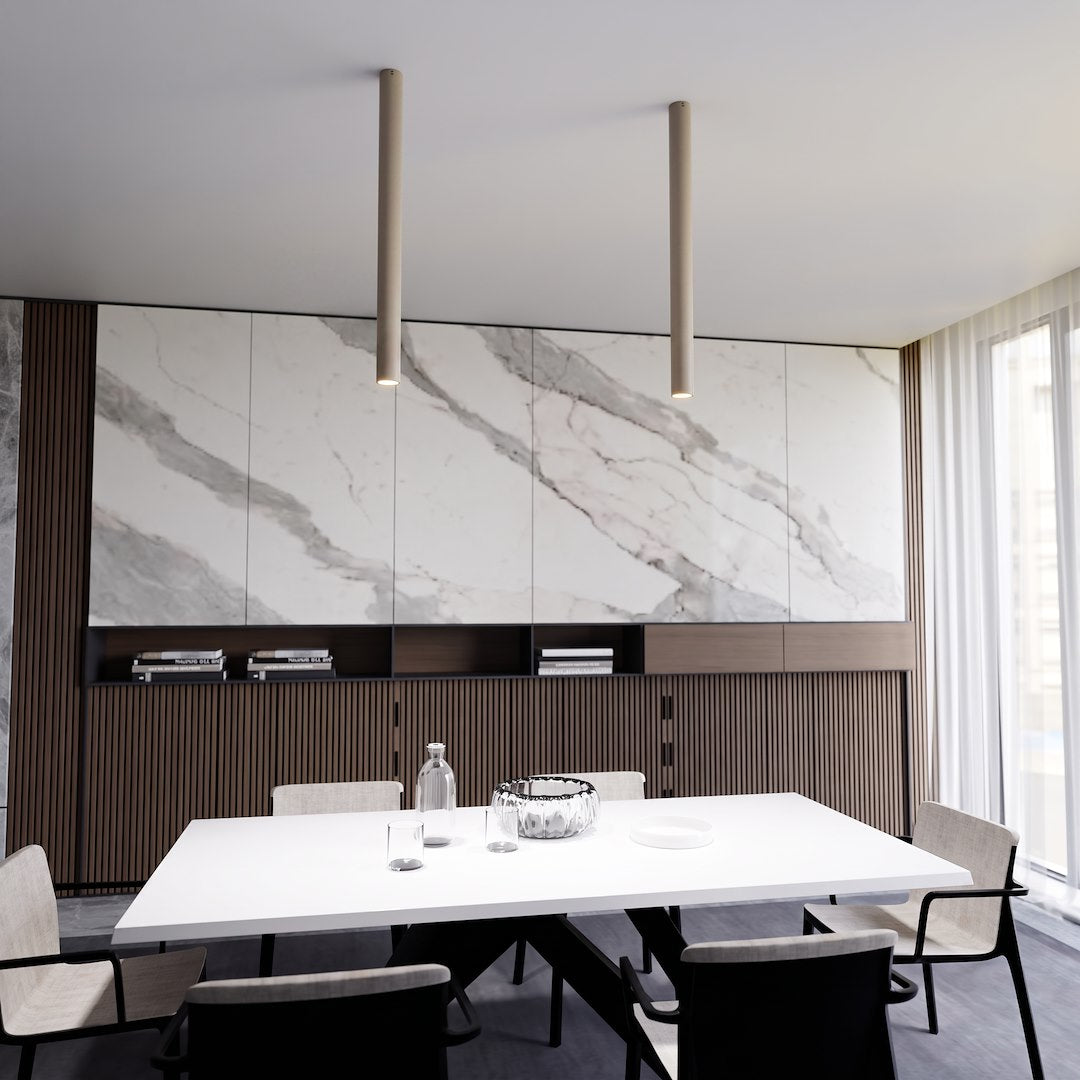 Deux longs tubes beige éclairent une salle à manger moderne et épurée.