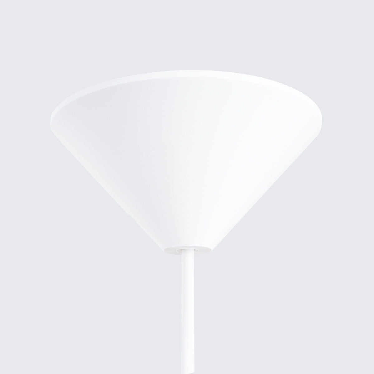 Gros plan sur la rosace conique blanche fixée au plafond et le câble.