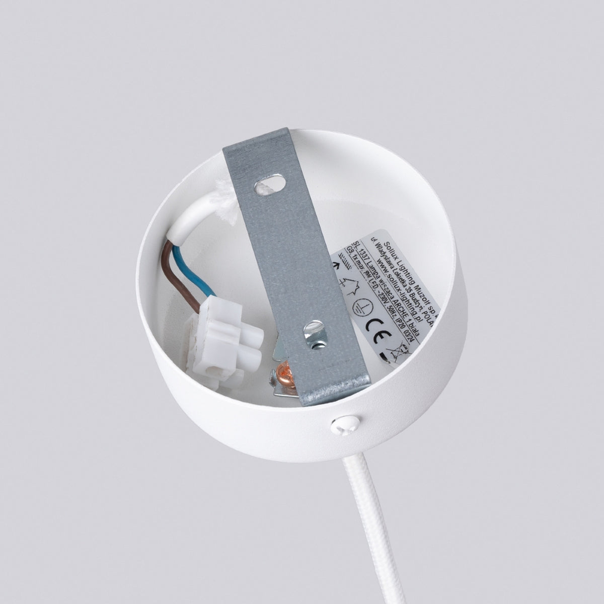 Détail du ciel de fixation : support métallique, câbles électriques et étiquette technique visibles.