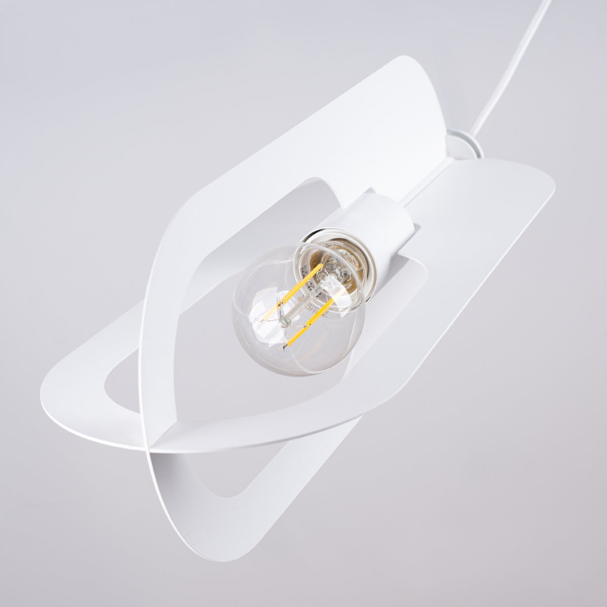 Gros plan sur un abat-jour blanc ovale ajouré et son ampoule transparente à filament.
