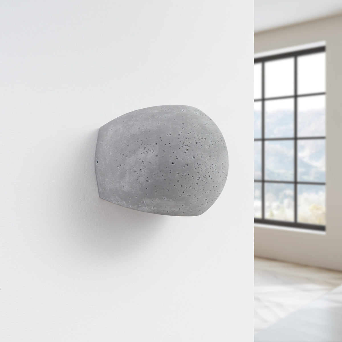 Applique en béton installée sur un mur blanc près d'une fenêtre