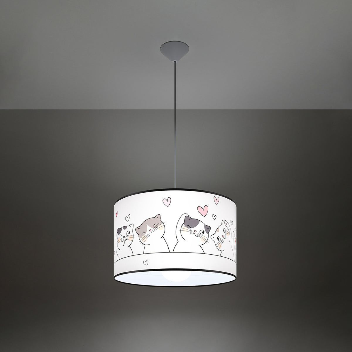 Lampe suspendue allumée dans une pièce sombre, diffuseur cylindrique aux motifs de chats éclairé.
