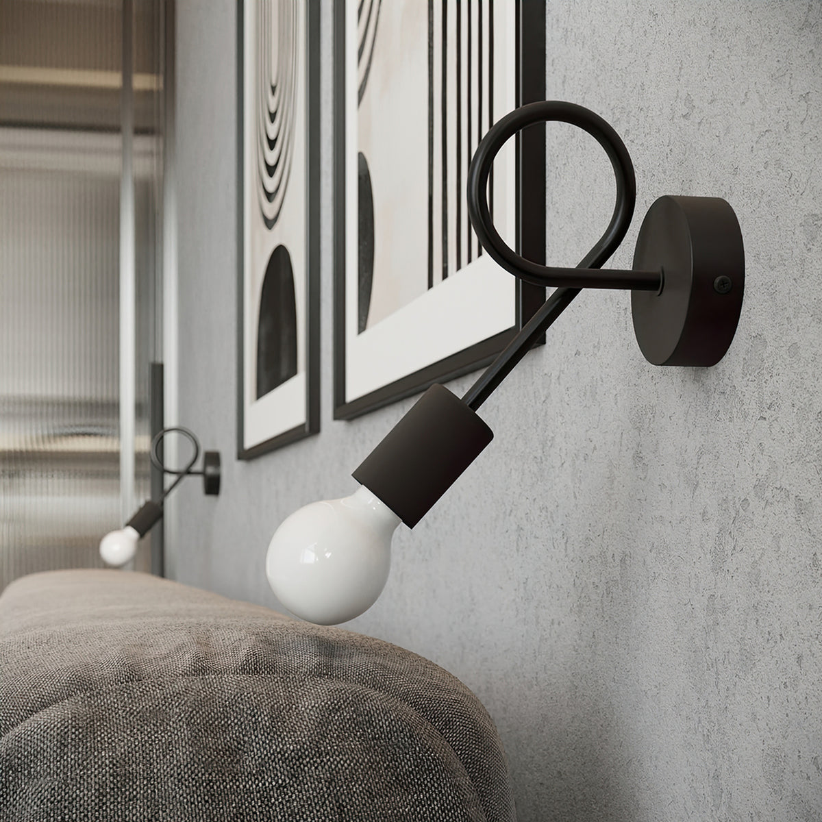 Mise en ambiance de l'applique noire fixée au mur au-dessus d'un canapé, avec cadres décoratifs.