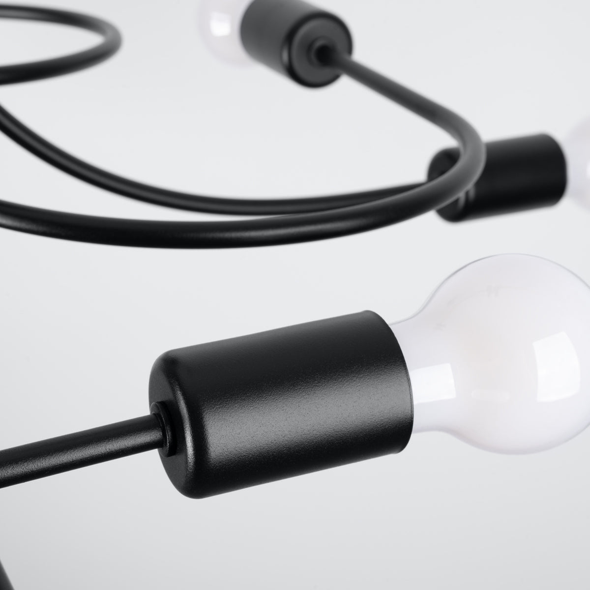 Gros plan sur une douille noire cylindrique et son ampoule blanche, finition mate.