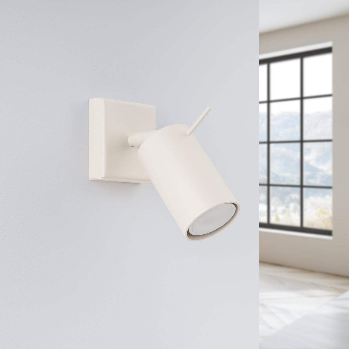 Applique murale beige installée sur un mur gris, près d'une fenêtre lumineuse.