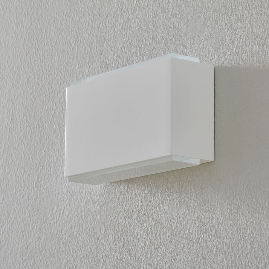 Vue de face de l’applique blanche éteinte, fixée au mur.