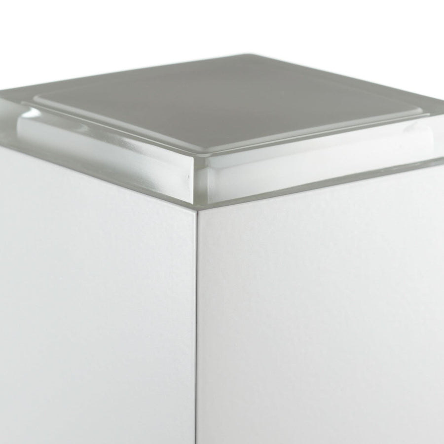 Détail du coin supérieur : épaisse plaque de verre clair posée sur le cube blanc.