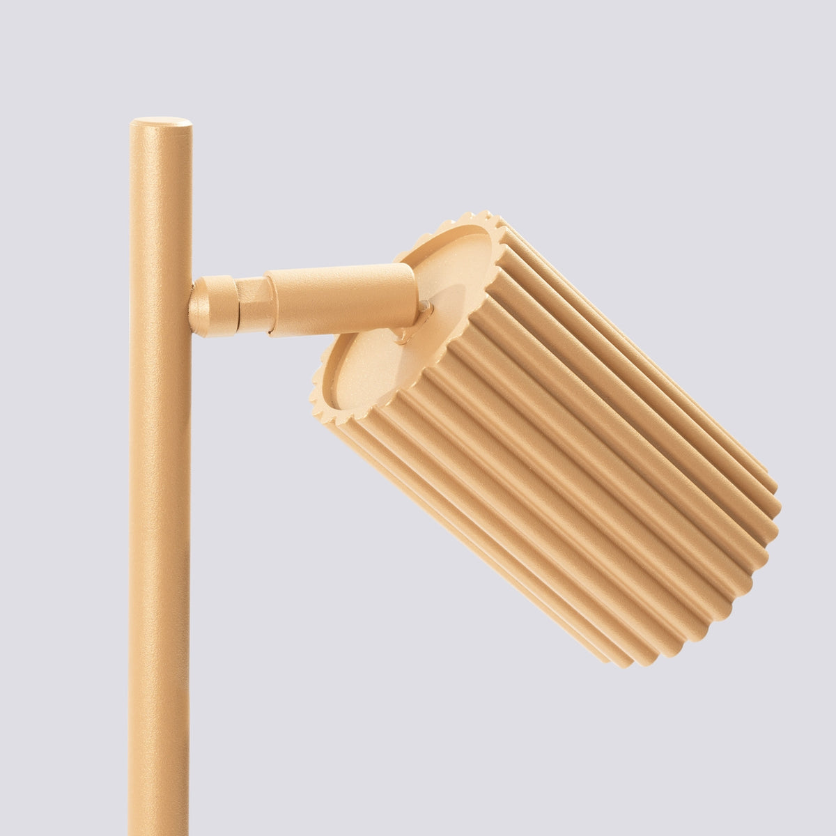 Gros plan sur l'abat-jour cylindrique strié et l'articulation métallique de la lampe.
