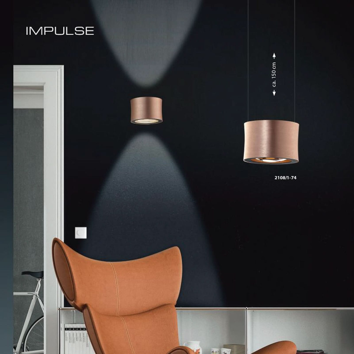 Mise en ambiance sur mur noir avec applique et suspension assortie, fauteuil orange.