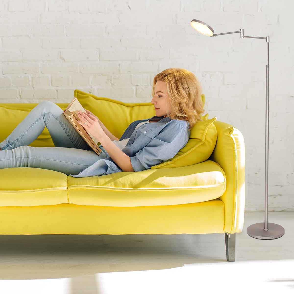Mise en ambiance, femme lisant sur canapé jaune éclairée par le lampadaire