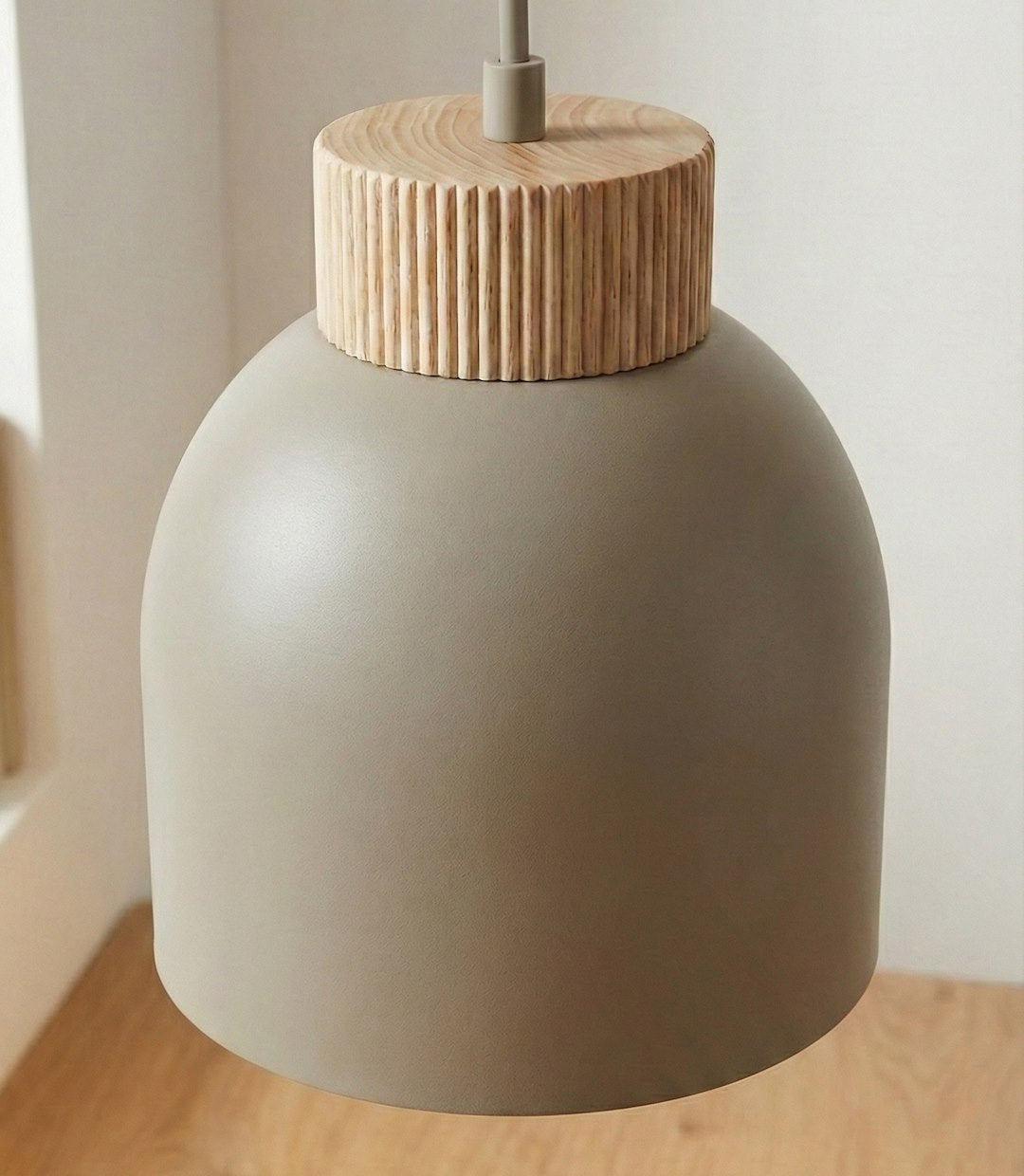 Gros plan du luminaire beige suspendu devant un mur clair