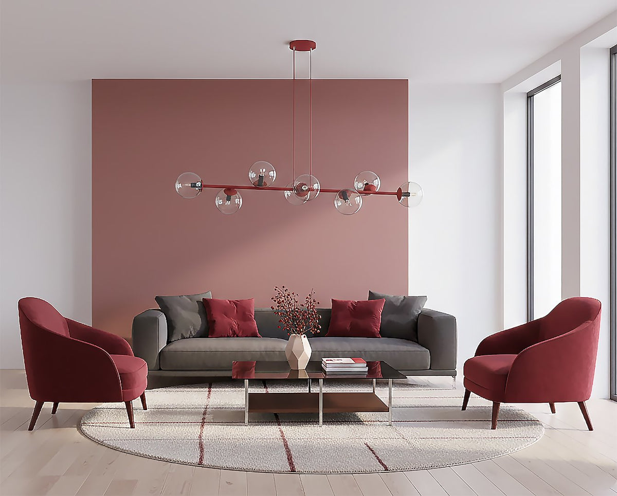 Mise en ambiance salon, canapé gris, fauteuils bordeaux et mur rose poudré
